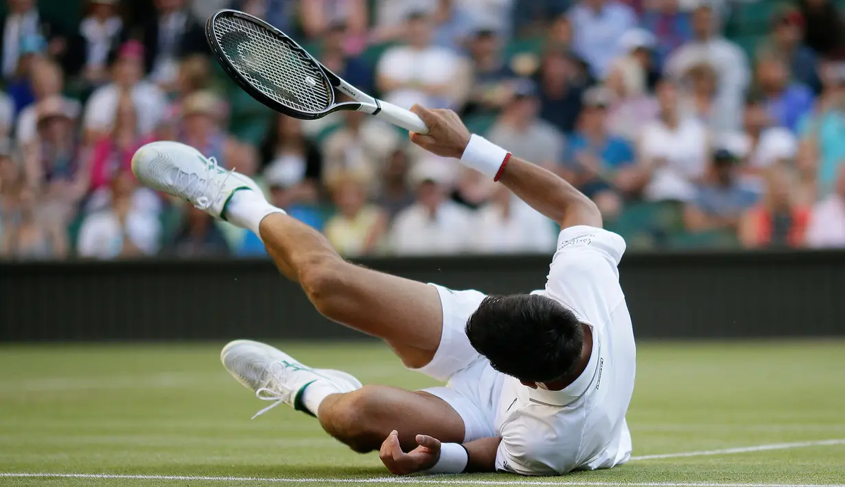 Petenis Serbia, Novak Djokovic jatuh tersungkur ketika menghadapi petenis AS, Denis Kudla pada babak kedua Wimbledon di All England Lawn Tennis Club, London, Kamis (4/7/2019) dini hari. Djokovic melangkah ke babak ketiga setelah menang dengan skor 6-3 6-2 6-2. (AP Photo/Tim Ireland)