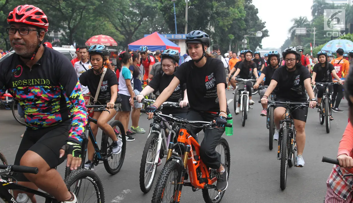 Artis peran Nadine Chandrawinata mengadakan kegiatan bersepeda sambil berkampanye gerakan #BebasButaHuruf di kawasan Sudirman, Jakarta, Minggu (13/). Kampanye itu dipelopori Komunitas Taman Bacaan Pelangi dan Sea Soldier. (Liputan6.com/Herman Zakharia)