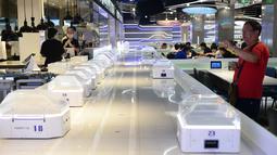 Pengunjung mengambil gambar sejumlah robot pintar sebesar oven microwave di restoran Robot.He milik Alibaba di Shanghai, 30 Juli 2018. Tugas robot itu mengangkat tutup kaca hidangan bergaya Shanghai dan mengucapkan, "Selamat menikmati hidanganmu". (AFP)