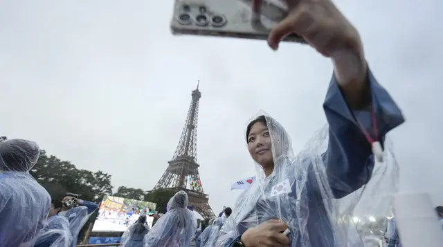 Asom Kim, fisioterapis dari tim Korea Selatan berfoto selfie dengan latar belakang Menara Eiffel dari atas kapal menyusuri Sungai Seine saat upacara pembukaan Olimpiade Paris 2024, Jumat (26/7/2024). (AP Photo/Lee Jin-man, Pool)