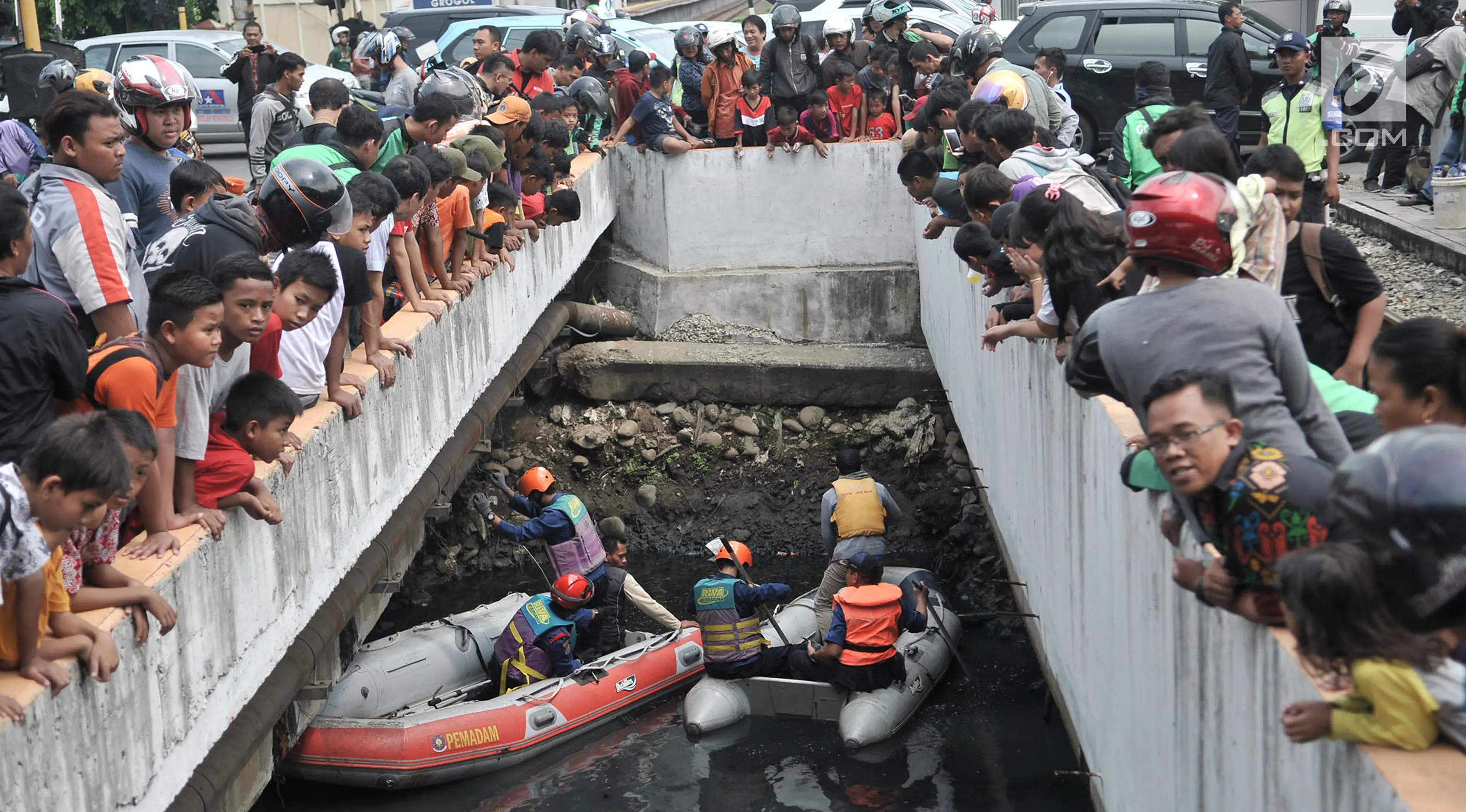 Warga dan pengendara berkerumun melihat upaya tim gabungan melakukan pencarian buaya di Kali Grogol, Jakarta Barat, Kamis (28/6). Pencarian telah dilakukan sejak kemarin siang ketika warga melaporkan penampakan buaya itu. (Merdeka.com/Iqbal S. Nugroho)