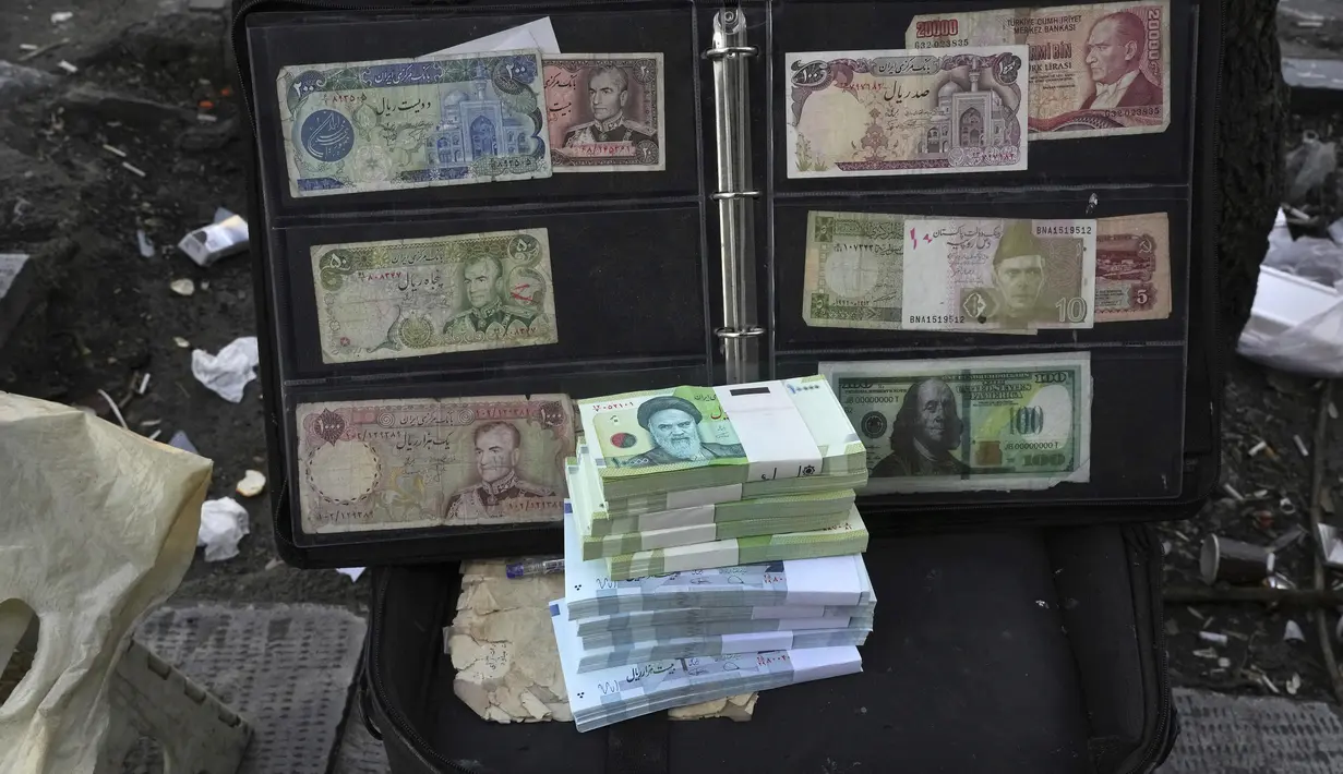 Uang kertas dan mata uang asing Iran saat ini dan sebelum revolusi ditampilkan oleh seorang penjual di distrik komersial di pusat kota Teheran, Minggu (26/2/2023). Mata uang Iran jatuh ke rekor terendah yang baru pada hari Minggu (26/2), yaitu anjlok ke 600.000 per 1 dolar Amerika, untuk pertama kalinya lantaran dampak terus berlangsungnya demonstrasi anti-pemerintah dan gagalnya upaya menghidupkan kembali perjanjian nuklir tahun 2015 yang terus menggerus ekonomi. (AP Photo/Vahid Salemi)