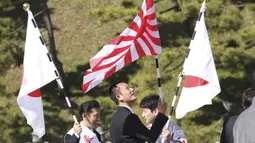 Simpatisan mengibarkan bendera nasional Jepang di dekat Istana Kekaisaran untuk merayakan ulang tahun ke-60 Kaisar Naruhito di Tokyo, Minggu, (23/2/2020). Kaisar Jepang Naruhito menandai ulang tahun dengan simpatinya kepada mereka yang terkena virus COVID-19. (AP Photo/Koji Sasahara)