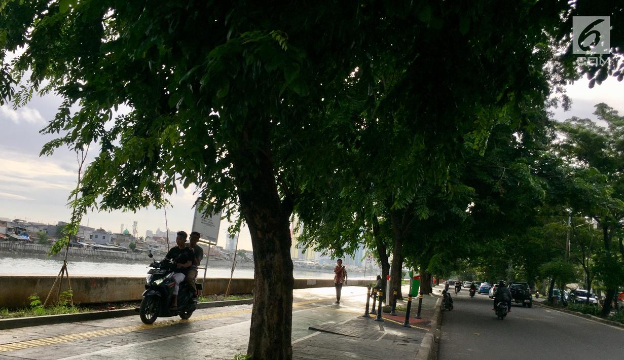 Warga mengendarai motornya melintasi trotoar di Danau Sunter, Jakarta, Jumat (19/1). Hal ini dikerenakan kurangnya kesadaran warga yang akhirnya merugikan pengguna trotoar semestinya, yaitu pejalan kaki. (Liputan6.com/Immanuel Antonius)