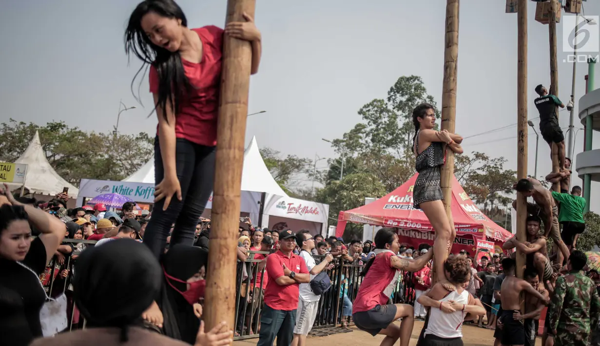 Sejumlah warga negara asing mengikuti panjat pinang kolosal dalam rangka merayakan HUT ke-74 Kemerdekaan RI di Pantai Karnaval, Ancol, Jakarta, Senin (17/8/2019). Sebanyak 174 batang pinang dengan beragam hadiah disediakan dalam lomba yang diikuti ratusan warga itu. (Liputan6.com/Faizal Fanani)