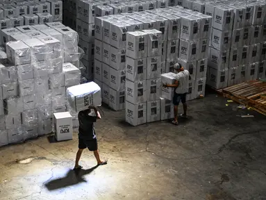 Pekerja menata kotak suara yang berisi surat suara sebelum dimasukkan ke dalam truk untuk didistribusikan ke kecamatan-kecamatan di gudang Komisi Pemilihan Umum (KPU) di Surabaya pada 5 Februari 2024. (Juni KRISWANTO/AFP)
