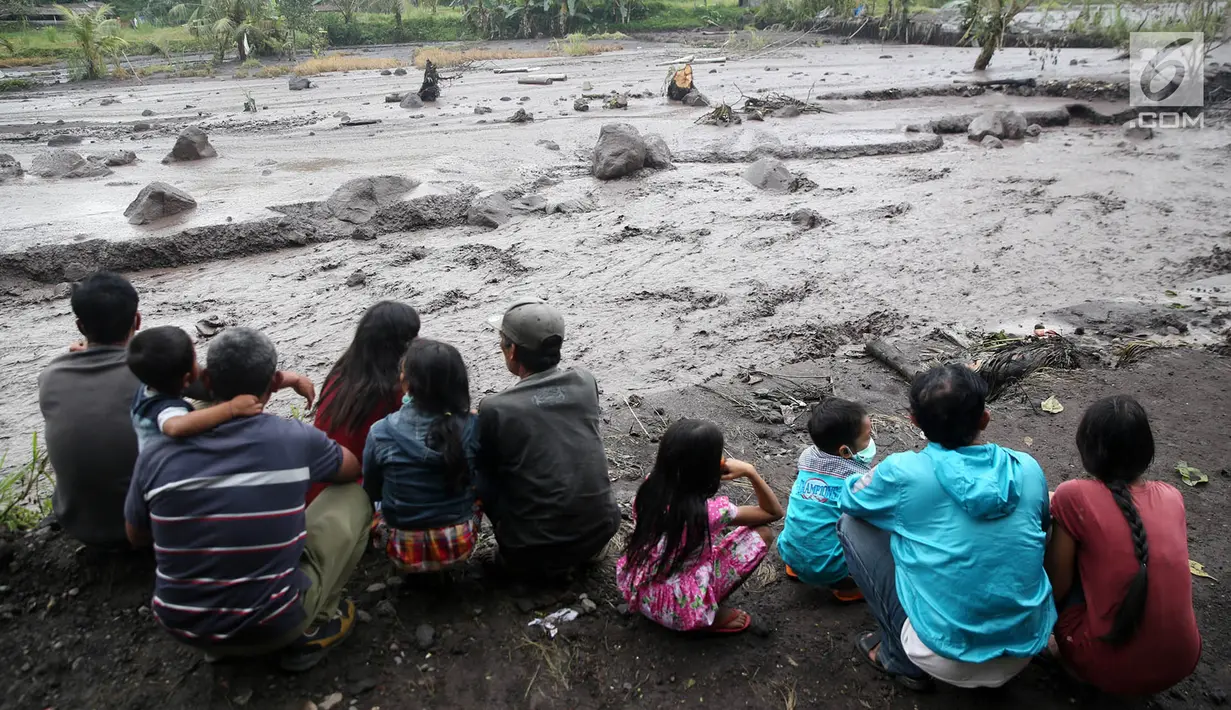 Warga mengamati aliran lahar dingin yang melintasi Sungai Yeh Sah di Karangasem, Bali, Sabtu (2/12). Banjir lahar dingin dari Gunung Agung tersebut mengundang perhatian warga sekitar. (Liputan6.com/Immanuel Antonius)
