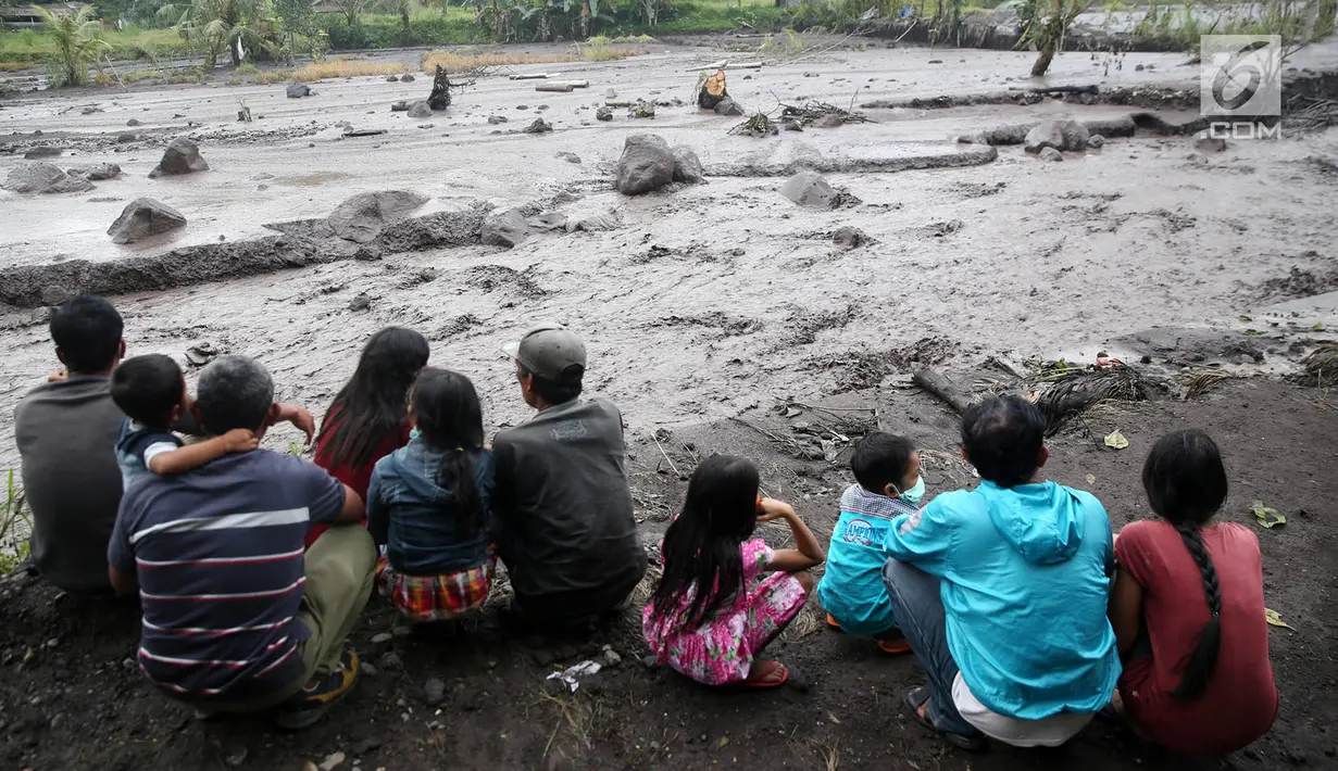 Warga mengamati aliran lahar dingin yang melintasi Sungai Yeh Sah di Karangasem, Bali, Sabtu (2/12). Banjir lahar dingin dari Gunung Agung tersebut mengundang perhatian warga sekitar. (Liputan6.com/Immanuel Antonius)