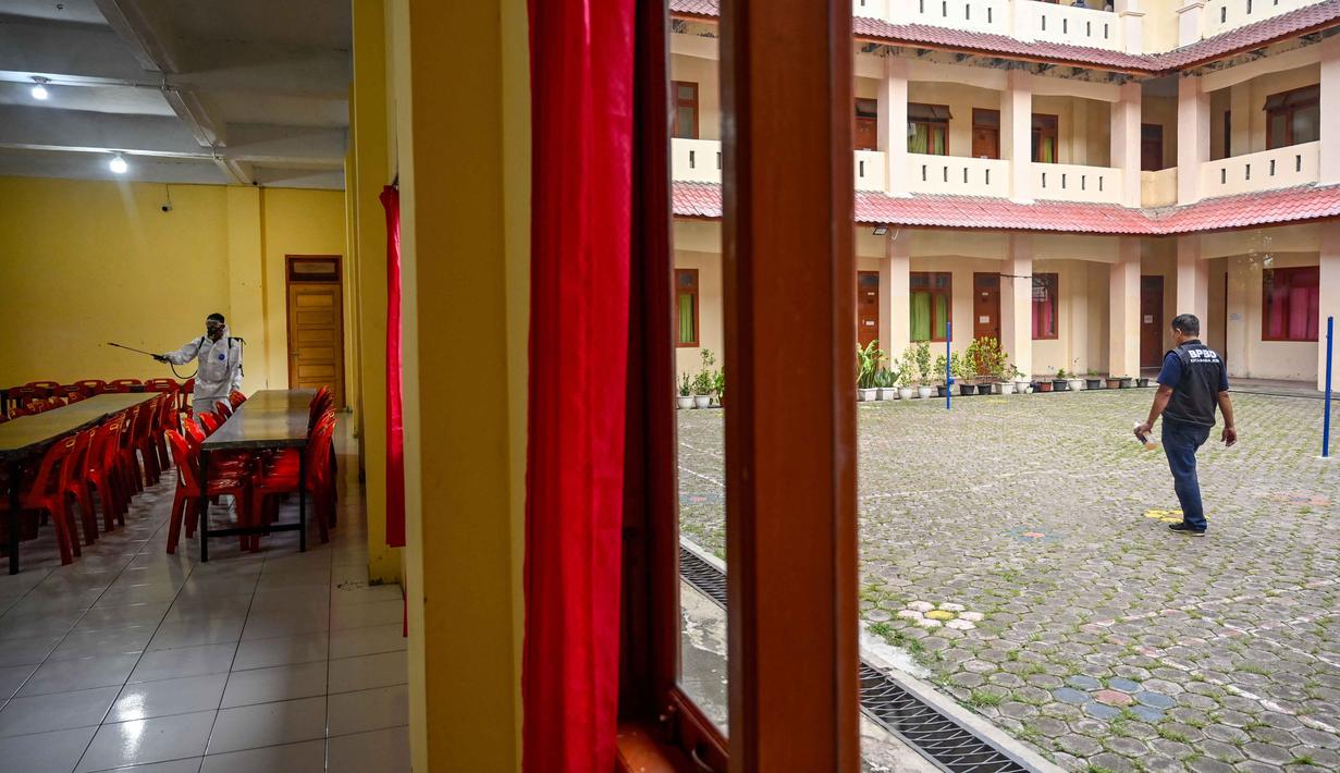 Seorang anggota Badan Penanggulangan Bencana Daerah (BPBD) menyemprotkan disinfektan di dalam ruang makan sebuah Sekolah Menengah Pertama (SMP) dalam rangka program mitigasi pencegahan penyebaran flu burung di Banda Aceh pada Jumat 31 Oktober 2025. Tim dari Badan Penanggulangan Bencana Daerah (BPBD) Kota Banda Aceh melakukan penyemprotan disinfektan ke beberapa sekolah menengah. (Chaideer MAHYUDDIN/AFP)
