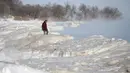 Seorang pria berjalan di Danau Michigan yang membeku saat suhu di bawah 0 derajat Celsius di Milwaukee, Rabu (30/1). Cuaca dingin ekstrem yang terjadi sekali dalam satu generasi sedang melanda beberapa wilayah Amerika Serikat. (AP/Jeffrey Phelps)