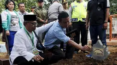 Seorang ulama (kiri) dan Iwan Setiawan, saudara laki-laki terpidana mati Zainal Abidin, saat prosesi pemakaman di TPU di Cilacap, Jateng, Rabu (29/4). Zainal satu-satunya terpidana mati asal Indonesia yang dieksekusi dini hari ini. (REUTERS/Beawiharta)