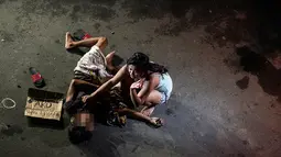Foto yang diambil pada 23 Juli 2016 menunjukkan Jennilyn Olayres (kanan) menangisi jasad suaminya yang tewas ditembak orang tak dikenal dan terkapar di samping karton bertuliskan “Saya bandar” di sebuah jalan di Manila, Filipina. (AFP PHOTO/Noel CELIS)