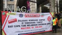 Petugas dari Pemprov DKI Jakarta memasang spanduk berisi peringatan kepada masyarakat untuk tidak membuang sampah sembarangan. Pemprov DKI menggunakan drone untuk memantau pembuang sampah sembarangan di Jakarta. (Merdeka.com)