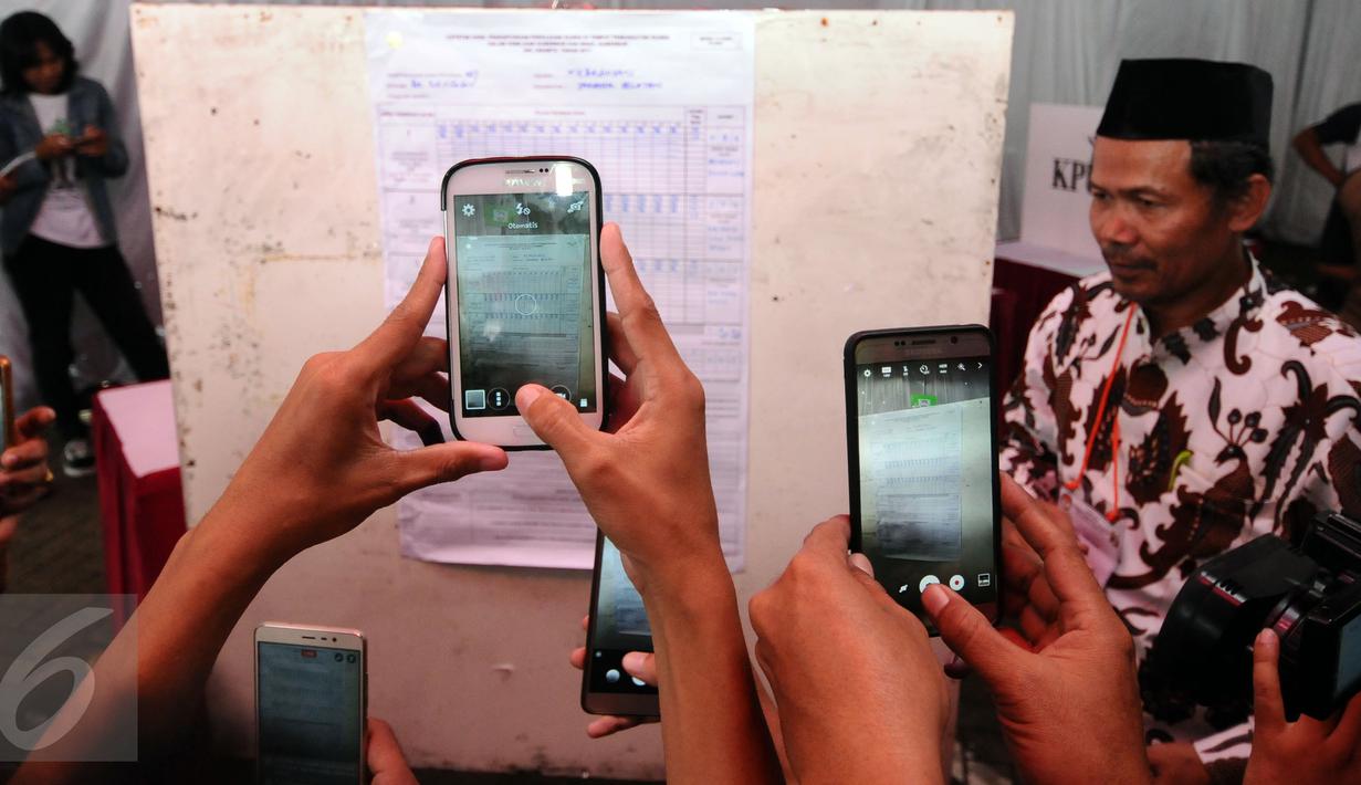 Warga mengabadikan hasil perolehan surat suara Pilkada DKI Jakarta di TPS 027 Kebagusan, Jakarta, Rabu (15/2). Ahok-Djarot unggul dengan 254 suara sementara Anies-Sandi 207 serta AHY-Sylvi 85. (Liputan6.com/Helmi Fithriansyah)