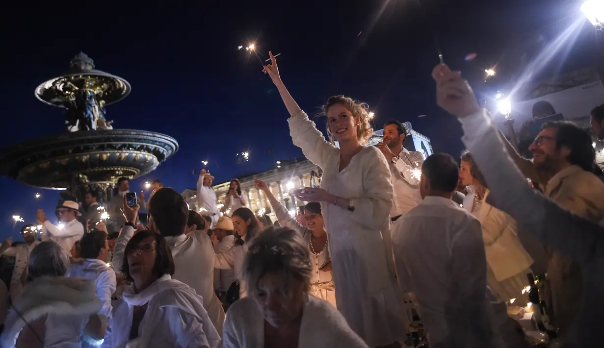 Para peserta dalam balutan serba putih  berkumpul untuk Dinner en Blanc atau "makan malam putih" di Tuileries Gardens, Paris, Kamis (6/6/2019). Sesuai tradisi, penyelenggara piknik pop-up ini merahasiakan lokasi acara tahunan ini sampai menit terakhir. (Lucas BARIOULET/AFP)