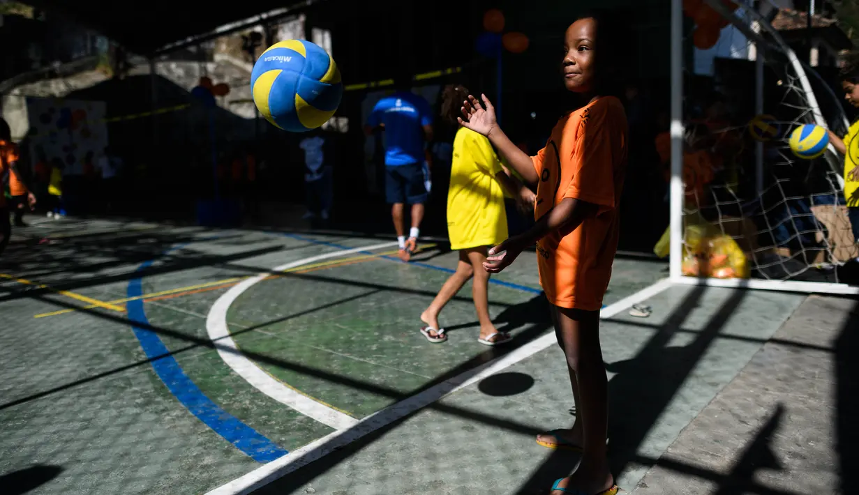 Seorang anak sedang mencoba memukul bola voli pada program Volleyball Development Training yang digagas oleh Federasi Bola Voli Internasional di Formiga favela, Rio de Janeiro, (2/8/2016). (AFP/Leon Neal)