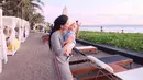 Nah kalau yang satu ini, terlihat Titi sedang menggendong buah hatinya sedang berlibur. Titi tetap cantik dengan dress abu-abunya saat menggendong Kai di tepi pantai. Lucu banget ya? (Instagram/titi_kamall)