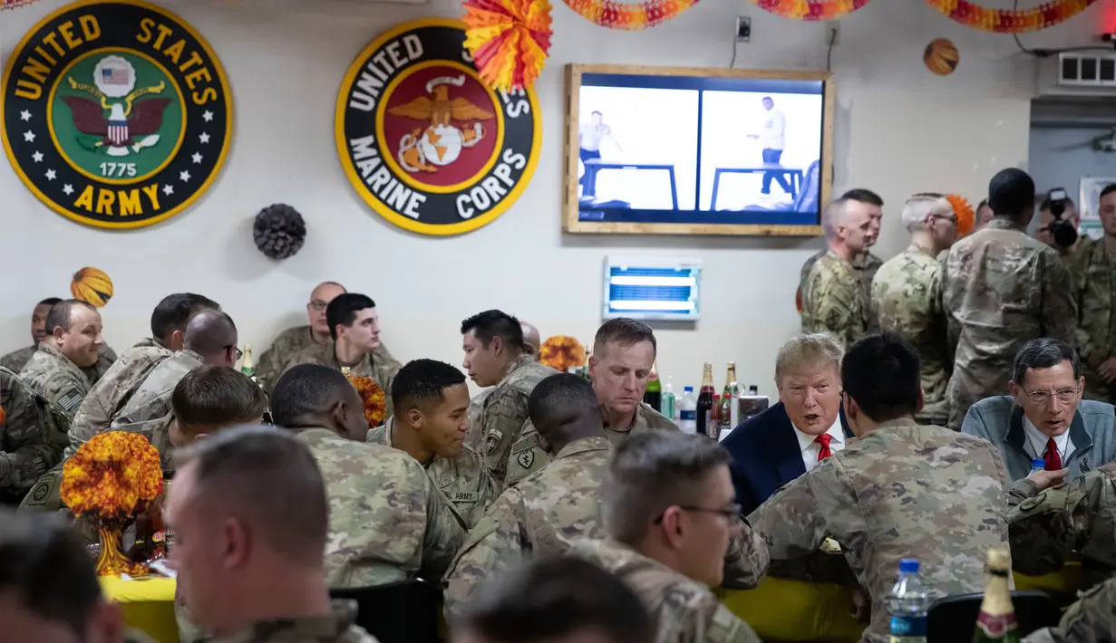 Presiden Amerika Serikat Donald Trump makan malam bersama para tentara saat mengunjungi Pangkalan Udara Bagram, Afghanistan, Kamis (28/11/2019). Kunjungan dadakan Trump pada hari Thanksgiving tersebut mengejutkan pasukan AS yang bertugas di Afghanistan. (AP Photo/Alex Brandon)
