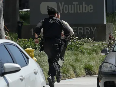 Petugas kepolsian berlari menuju kantor pusat YouTube merespon laporan insiden penembakan di San Bruno, California, Amerika Selatan, Selasa (3/4). Sebanyak tiga orang mengalami cedera akibat tembakan yang dilepaskan seorang perempuan.  (AP/Jeff Chiu)