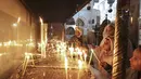 Peziarah dan turis menyalakan lilin menjelang Natal di dalam Gereja Kelahiran Yesus di kota Bethlehem, Tepi Barat pada 22 Desember 2022. Beberapa tempat indah yang diincar pengunjung menyambut Natal di Kota Bethlehem adalah Gereja Kelahiran yang sudah berusia ratusan tahun. (AFP/Hazem Bader)
