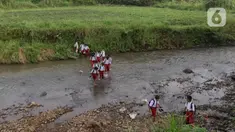 Sejumlah pelajar Sekolah Dasar (SD) menyeberangi sungai Cihideung untuk menuju sekolah mereka di Kampung Sempur, Kabupatan Bogor, Jawa Barat, Selasa (15/4/2025). (Liputan6.com/Herman Zakharia)
