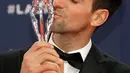 Petenis Serbia, Novak Djokovic mencium trofi seusai meraih penghargaan World Sportsman of the Year dalam ajang Laureus World Sports Awards 2019 di Monako, Senin (18/2). Ini merupakan penghargaan Laureus ke-4 bagi Djokovic. (AP/Claude Paris)