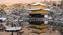 Halaman kuil Kinkakuji - Paviliun Emas - tertutup salju setelah salju tebal dan angin kencang semalaman mempengaruhi wilayah luas negara itu di Kyoto, Jepang, Rabu (25/1/2023). Salju turun di utara Jepang saat massa udara dingin mengalir ke kepulauan itu. (Photo by JIJI Press / AFP)