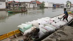 Pekerja mengangkut barang menggunakan perahu menuju dermaga di Desa Pantai Mekar, Muaragembong, Kabupaten Bekasi, Senin (6/12/2021). Jasa angkut barang menggunakan perahu tersebut bertarif Rp 3.000 per 15 kg. (Liputan6.com/Herman Zakharia)