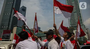 Sejumlah warga yang melintas mengibar-ngibarkan bendera Merah Putih saat melintasi kawasan Bundaran Hotel Indonesia, Jakarta, Sabtu (17/8/2024). (Liputan6.com/Angga Yuniar)