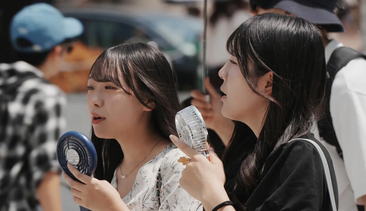 Badan Meteorologi Jepang mengeluarkan peringatan mengenai cuaca panas ekstrem yang kembali melanda sejumlah wilayah pada Selasa, 5 Agustus 2025. Tampak dalam foto, pejalan kaki menggunakan kipas angin genggam mereka di Tokyo pada 5 Agustus 2025. (Kazuhiro NOGI/AFP)