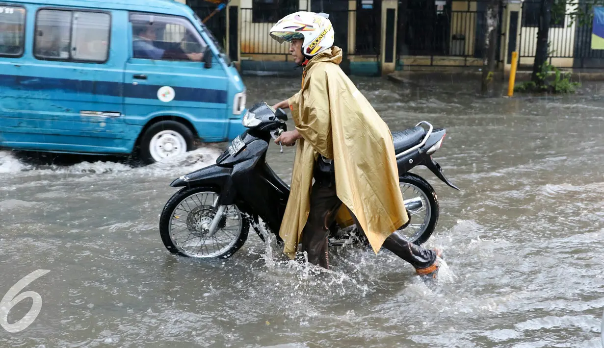 Pengedara motor mendorong motornya yang mogok akibat menerobos banjir di jalan Depok, Jumat (12/2). Badan Meteorologi, Klimatologi, dan Geofisika (BMKG) menyatakan bahwa Indonesia akan memasuki puncak musim hujan. (Liputan6.com/Yoppy Renato)