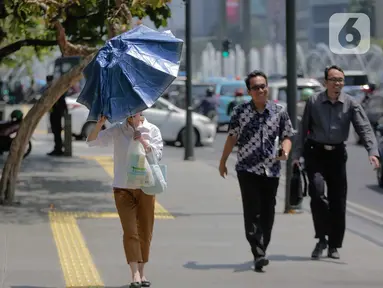 Seorang wanita merapikan payung selama gelombang panas di Jakarta, Selasa (22/10/2019).  BMKG memprediksi wilayah Indonesia akan mengalami panas selama kurang lebih satu minggu ini. Hal ini dikarenakan matahari yang berada dekat dengan jalur khatulistiwa. (Liputan6.com/Faizal Fanani)