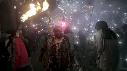 Seorang warga berpakaian seperti hantu dengan memegang tongkat kembang api selama perayaan " Correfocs ", Mallorca, Spanyol, (24/1). Orang - orang menari sambil men yalakan kembang api diantara kerumunan. (REUTERS / Enrique Calvo)