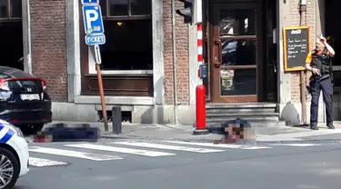 Seorang petugas polisi berdiri di lokasi dekat dua jenazah polisi korban penembakan di Liege, Belgia (29/5). Seorang pria menembak mati tiga orang di dekat sebuah kafe di Kota Liege, Belgia, Selasa waktu setempat. Dua di antara korban adalah polisi. (AP)