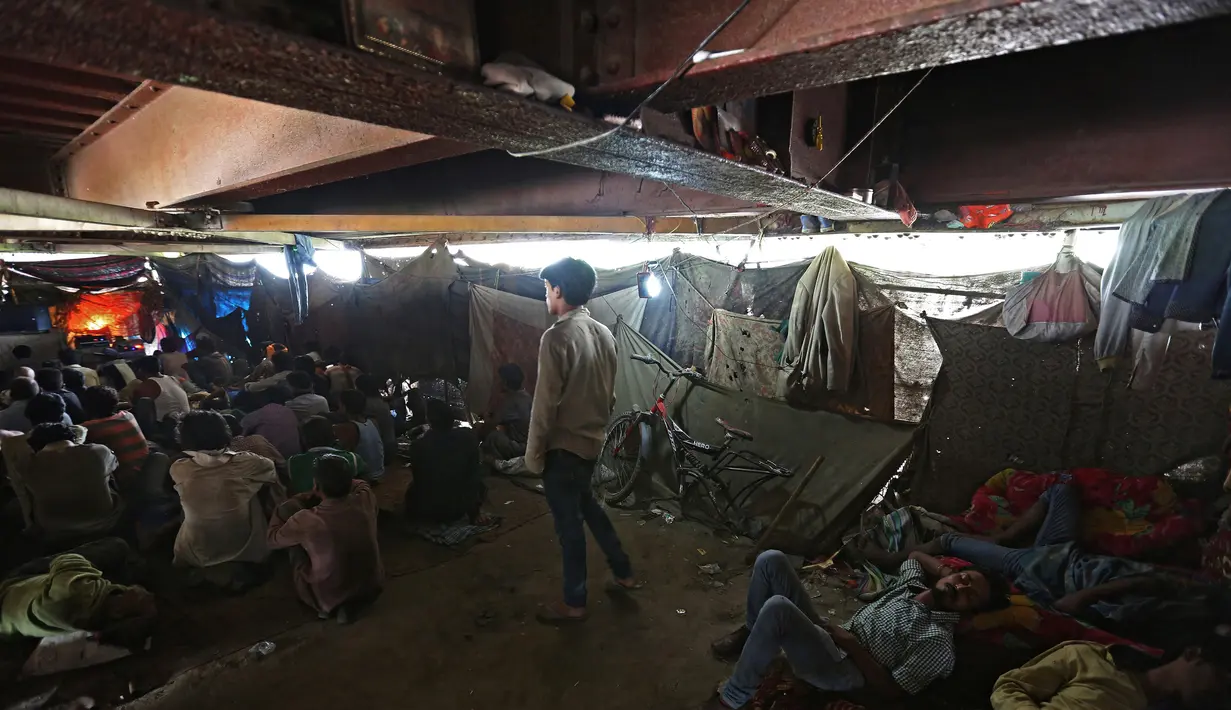 Sejumlah orang menonton film di bioskop darurat yang terletak di bawah jembatan di kuartal tua Delhi, India (25/5). Bioskop ini berada di bawah jembatan berusia 140 tahun di ibukota India. (REUTERS/Cathal McNaughton)