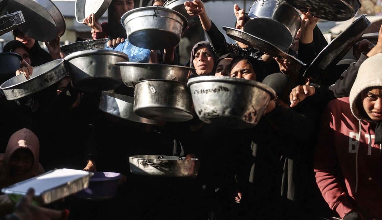 Sebelumnya, militer Israel menutup semua akses ke Gaza pada Sabtu (28/2/2026) setelah mengumumkan serangan udara terhadap Iran yang dilakukan bersama dengan Amerika Serikat. Tampak dalam foto, warga Palestina yang mengungsi berebut untuk makanan di Khan Younis, selatan Jalur Gaza pada Jumat 6 Maret 2026. (Bashar Taleb/AFP)