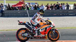 Pembalap Spanyol Repsol Honda, Marc Marquez membawa bendera di atas motor setelah memenangkan balapan seri ke 18 MotoGP Grand Prix Valencia di Sirkuit Ricardo Tormo, Valencia (12/11). Marc Marquez finis di urutan ketiga. (AFP PHOTO / Jose Jordan)