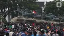 Massa aksi demo tolak omnibus law UU Cipta Kerja naik ke atas patung arjuna wiwaha mengibarkan bendera merah putih di Jalan Medan Merdeka Barat, Jakarta Pusat, Selasa (20/10/2020). Mereka sempat mengibarkan bendera selama kurang lebih lima menit di atas patung. (Liputan6.com/Herman Zakharia)