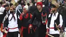 Sekelompok pemain cerita rakyat dari wilayah timur Iran berjalan saat musisi daerah Kurdi memainkan Daf, drum Persia genggam, dalam upacara menjelang Tahun Baru Iran, atau Nowruz, di sebuah taman di Teheran, Iran (14/3/2022). Nowruz akan diselenggarakan pada 20 Maret. (AP Photo/Vahid Salemi)