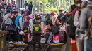 Para penumpang menyeberang rel saat bersiap naik kereta di stasiun Gubeng, Surabaya, Jawa Timur, Selasa 17 Maret 2026. PT Kereta Api Indonesia (KAI) Daop 8 Surabaya mencatat lonjakan penumpang pada masa angkutan Lebaran 2026. (JUNI KRISWANTO/AFP)