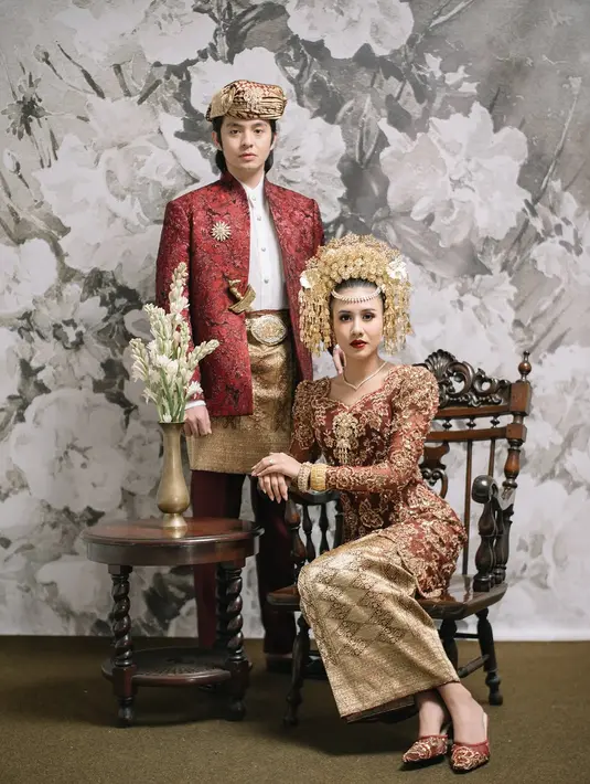 Shenina tampil menawan dengan suntiang megah khas Minang, kebaya merah marun beraksen emas, serta kain songket yang melengkapi tampilan tradisionalnya. Angga pun tampil gagah dengan setelan adat Minang berwarna senada, dipadukan dengan jas motif ukiran dan destar yang mencerminkan sosok pria Minang yang berkarisma. [@angga].