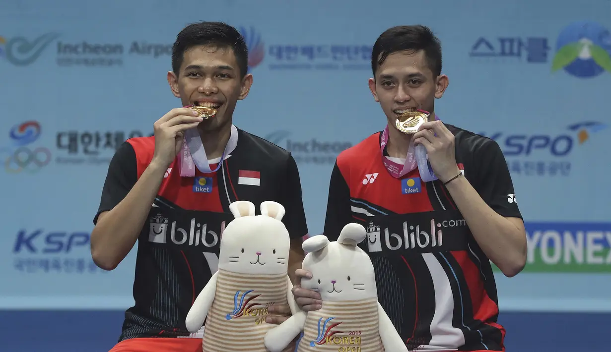 Ganda putra Indonesia, Fajar Alfian/Muhammad Rian Ardianto mengigit medali usai mengalahkan Takeshi Kamura/Keigo Sonoda pada final Korea Terbuka 2019 di Incheon (29/9/2019). Fajar /Rian menang atas Takeshi Kamura/Keigo Sonoda 21-16, 21-17. (AP Photo/Ahn Young-joon)