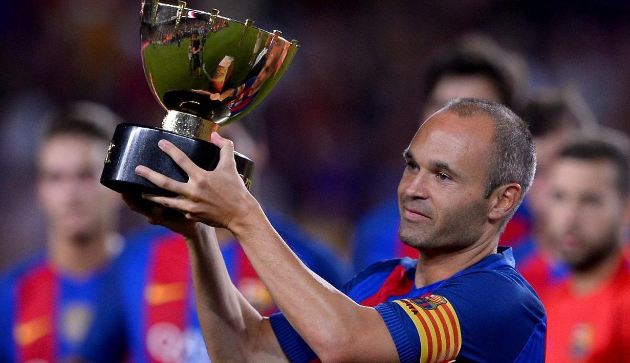 Kapten Barcelona, Andres Iniesta, mengangkat trofi juara Trofeo Joan Gamper 2016 di Camp Nou, Kamis (11/8/2016) dini hari WIB. (AFP/Josep Lago)