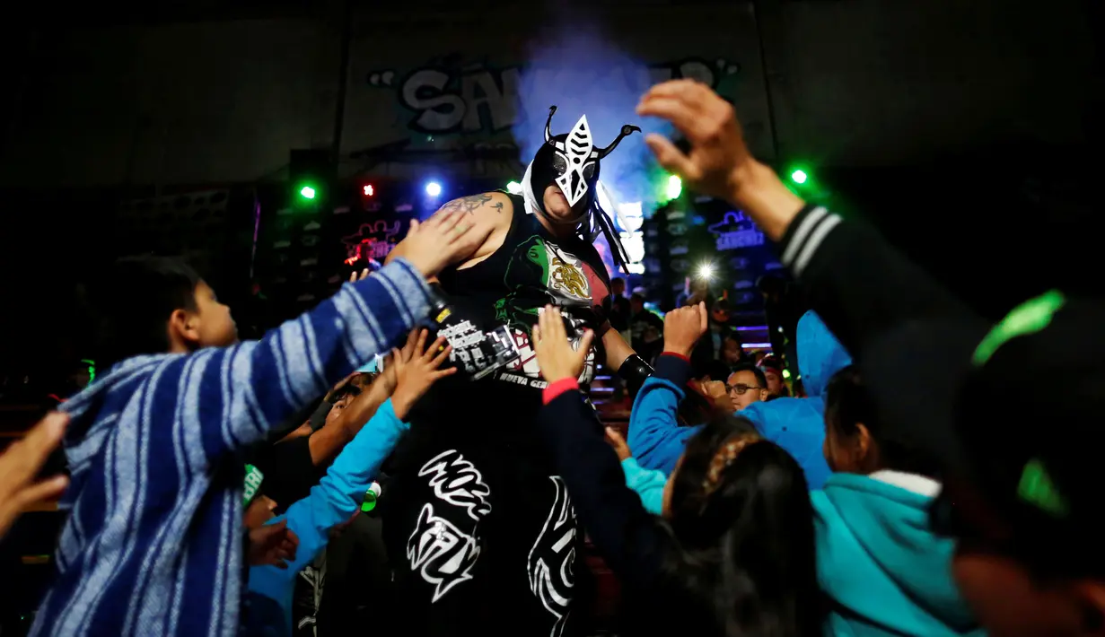 Pegulat yag dikenal Mosco X-Fly dikerumuni penonton saat memasuki ring dalam pertandingan gulat ekstrim di Arena Neza di pinggiran Mexico City, Meksiko (28/10). (Reuters/ Carlos Jasso)
