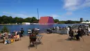 Warga bersantai di dekat pembangunan 'The Mastaba', sebuah karya luar ruangan yang terdiri dari lebih dari 7.000 tumpukan tong oleh seniman Bulgaria Christo Vladimirov Javachef di danau Serpentine di Hyde Park di London (11/6). (AFP Photo/Niklas Hallen)