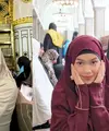 Pada foto pertama, Rebecca terlihat mengenakan busana syari berwarna maroon yang memberi kesan hangat dan elegan. Khimar panjang yang menjuntai menciptakan siluet flowy yang feminin. Duduk di atas kursi bermotif khas Timur Tengah, tampilannya terasa estetik dengan perpaduan warna yang kontras namun tetap harmonis. Riasan wajahnya tampak natural dengan sentuhan lipstik bernuansa merah lembut yang mempertegas kecantikan wajahnya. [@rklopper].