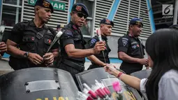 Petugas Brimob menerima bunga dari peserta aksi komunitas Spartan Nusantara di sekitar Gedung Bawaslu, Jakarta, Minggu (26/5/2019). Aksi tersebut sebagai bentuk terima kasih kepada TNI/Polri karena setia dan menjaga keamanan NKRI terkait sengketa pemilu. (Liputan6.com/Faizal Fanani)