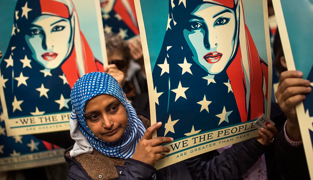 Seorang wanita membawa poster saat reli menentang kebijakan travel ban tujuh negara mayoritas Muslim yang dikeluarkan oleh Presiden Trump di New York Times Square, AS, Minggu (19/2). (AP/Andres Kudacki)