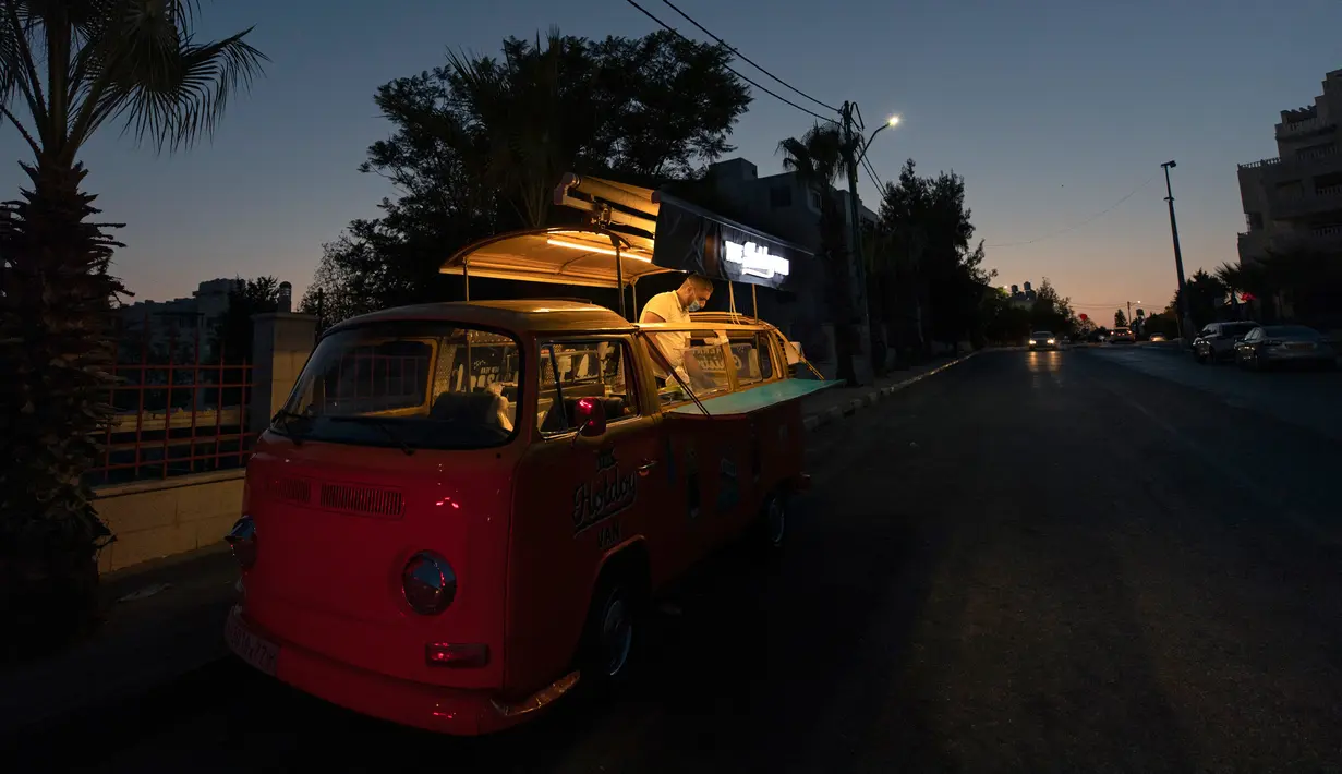 Seorang pria menjual hot dog dan minuman dari mobil van yang telah diubah di Ramallah, Tepi Barat, 23 September 2020. Dengan sebagian besar restoran tutup karena pembatasan COVID-19, food truck telah memungkinkan pengusaha Palestina untuk menemukan cara tetap bekerja. (AP Photo/Nasser Nasser)