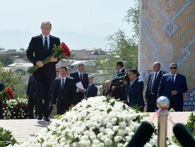 Presiden Rusia Vladimir Putin membawa bunga mawar saat mengunjungi makam mendiang Presiden Uzbekistan Islam Karimov di kota Samarkand, Selasa (6/9). Karimov meninggal di usia 78 tahun pada Jumat (2/9). (Sputnik/Kremlin/Alexei Druzhinin/ REUTERS)